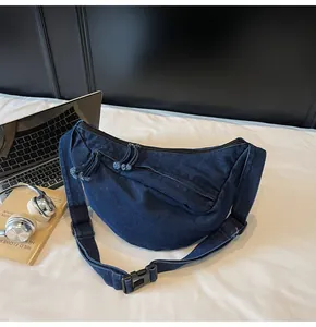 Detailed close-up of dark blue denim crescent bag with large capacity and zippers