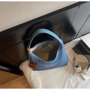 Détail du sac cabas en toile bleue avec des anses en similicuir et une fermeture magnétique