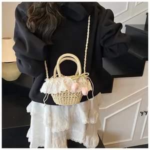 Vue détaillée d'un sac seau en paille avec bordure en dentelle et breloques de tulipes
