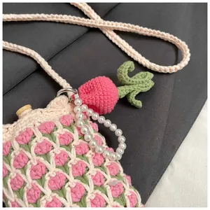 Detail of handmade crochet tulip bag featuring white yarn, pink flowers, and pearl strap
