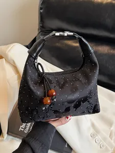 Satin dumpling handbag with rhinestones and amber bead pendant on a leather sofa