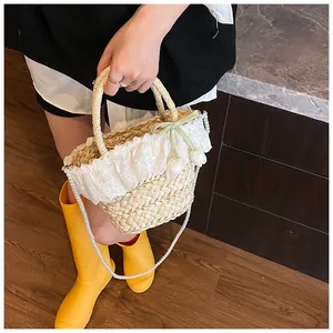 Détail du sac en paille avec bordure en dentelle, ruban vert, tulipes et bandoulière perle