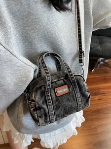 Retro denim bowling bag in faded black with vintage crossbody strap and metal logo plate