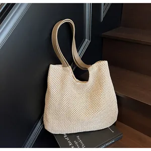 Detail of woven straw texture and premium brown leather handles on a beige tote bag