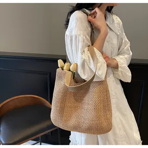 Detail of woven straw tote bag with wide strap and tulip decor against a white dress