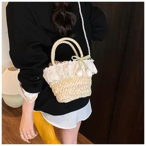 Détail du sac en paille avec bordure en dentelle, bandoulière en perles et nœud ruban
