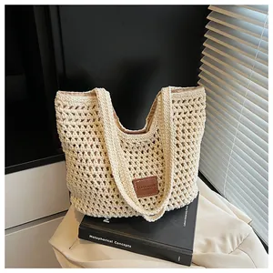 Detail of crochet weave texture and brown leather logo on cream woven beach tote bag