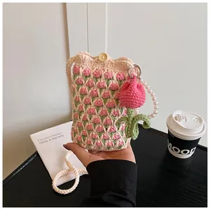Detail of hand-crocheted tulip crossbody bag with pearl handle and wooden button closure