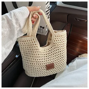 Close-up of beige crochet tote bag featuring intricate woven texture and leather brand tag