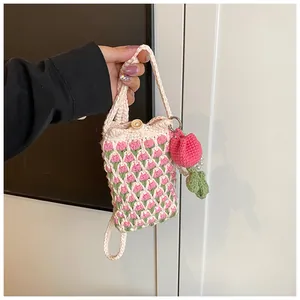 Close-up of handmade crochet tulip mini crossbody bag with a wooden button and flower charm