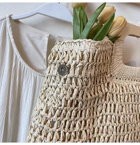 Detail of woven straw handbag featuring tight knit texture and magnetic silver buckle closure