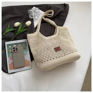Detailed close-up of a cream crochet woven tote bag with a brown leather logo patch