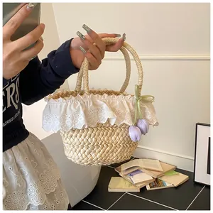 Détail du sac à main en paille tressée avec bordure en dentelle et breloques de tulipes