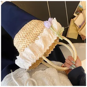 Détail du sac en paille avec dentelle blanche, tulipes mauves et nœud vert
