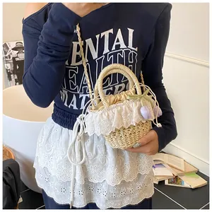 Détail d'un sac en paille beige avec bordure en dentelle blanche et charm tulipe