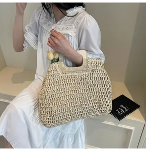 Detail of beige hollow woven straw tote bag featuring square wooden handles for summer
