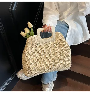 Detailed texture of beige woven straw tote bag with rectangular wooden handle and tulip accent