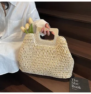 Detail of hand-woven beige beach bag with rectangular wooden handle on wooden stairs
