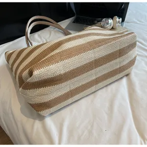 Close-up of the woven texture on a large capacity straw tote bag with brown and beige stripes