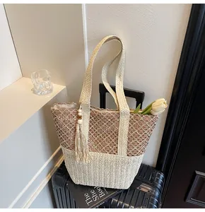 Detalle de bolso tote trenzado con diseño de malla calada y borla sobre maleta