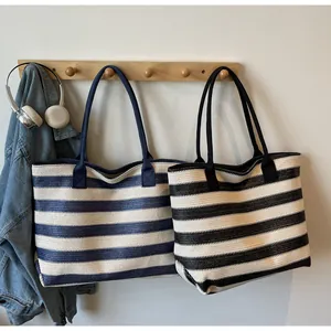 Detail of striped woven tote bags in blue and black hanging on a wooden hook