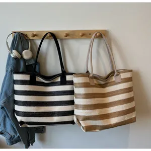 Detailed close-up of striped woven tote bags in black and brown hanging on hooks