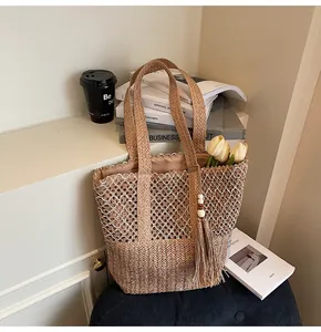 Detalle de bolso tote tejido con diseño de malla hueca y borla decorativa con cuentas
