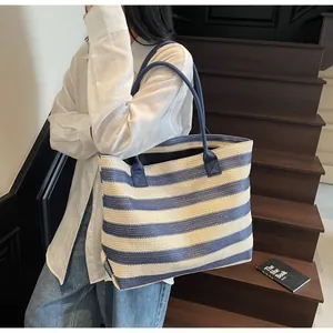 Blue and white striped woven tote bag styled with a casual outfit on wooden stairs