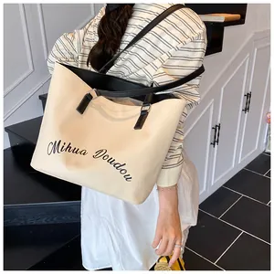 Detail of the large beige canvas tote bag with black leather handles and printed art text