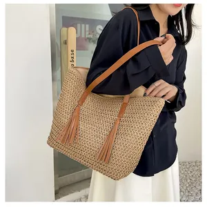 Detail einer gewebten Strohtasche mit braunen Lederquasten und natürlicher Holztextur