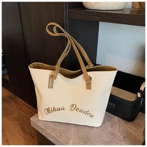 Close-up of beige leather tote bag with Mihua Doudou script and brown slim straps