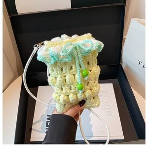 Macro detail of hand-crocheted mini bag with frill trim and green drawstring closure