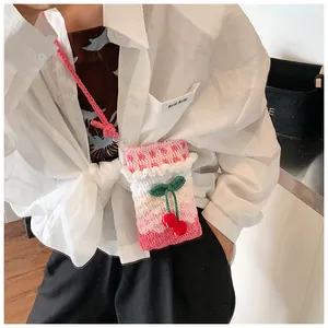 Detail der handgestrickten Umhängetasche mit 3D-Kirschen und Rüschendesign