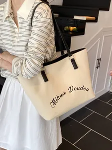 Minimalist canvas tote bag with black leather handles and elegant cursive text