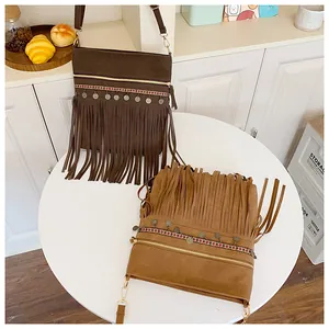 Detail of bohemian fringe crossbody bags with ethnic embroidery and metal disks