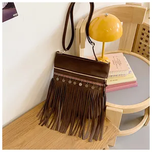Detailed close-up of dark brown bohemian fringe crossbody bag with metal disc accents