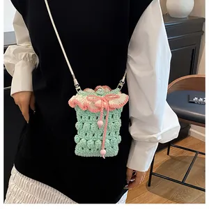Detail of mint green crochet phone bag with pink ruffled edges and pearl button closure