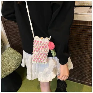 Detail of hand-woven tulip crochet bag with pearl strap and strawberry charm