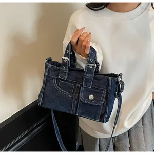 Macro detail of dark blue washed denim bag featuring metal hardware and stitching