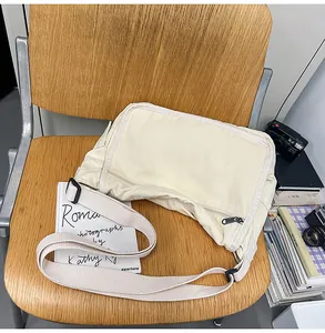 Detailed close-up of a cream-colored canvas messenger bag on a rustic wooden chair