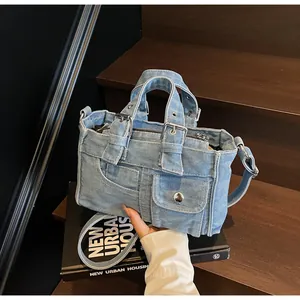 Detail of light blue washed denim handbag featuring metal buttons and front pockets