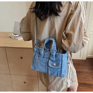 Detailed view of blue washed denim crossbody bag with silver buckles and leather straps