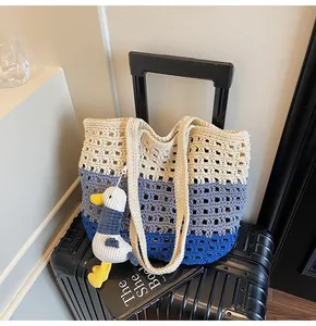 Detail of hollow knit tote bag with tri-color stripes and a small plush charm accessory