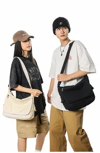 Detail of adjustable wide shoulder strap and zippers on durable canvas messenger bag
