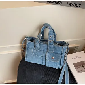 Macro shot of light blue denim handbag showing durable fabric texture and metal buckle detail