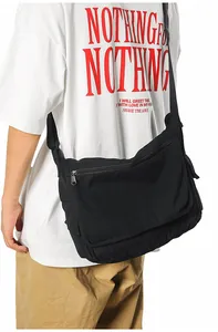 Detailed side view of the large capacity black canvas messenger bag on a male model