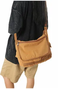 Macro detail of brown canvas messenger bag showing large capacity and flap cover