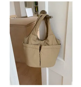 Sac fourre-tout matelassé kaki avec deux poches avant, accroché à une porte blanche