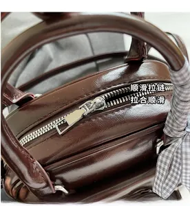Détail de la fermeture éclair argentée sur sac à main en cuir marron avec foulard