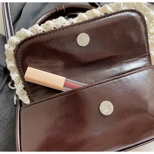 Gros plan du sac en cuir verni marron chocolat avec poche frontale et bordure en dentelle